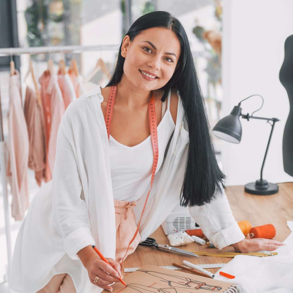 Woman in a clothing design studio with sewing tools and fabric.