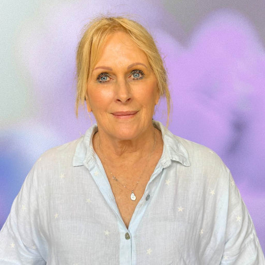 Person wearing a light blue shirt with a blurred purple background